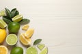 Fresh ripe lemons, limes and green leaves on white wooden background, flat lay. Space for text Royalty Free Stock Photo