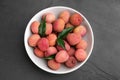 Fresh ripe lychee fruits in white ceramic bowl on black table, top view Royalty Free Stock Photo