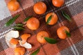 Fresh ripe mandarins with green leaves are on orange wool plaid. Harvesting. Healthy food concept. Top view, flat lay, Royalty Free Stock Photo