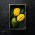 Fresh ripe mango on black stone background. Tropical fruits. Top view. Royalty Free Stock Photo