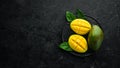 Fresh ripe mango on black stone background. Tropical fruits. Top view. Royalty Free Stock Photo