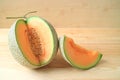 Fresh ripe muskmelon whole fruit with a piece of sliced fruit on a wooden table