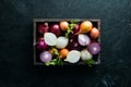Fresh ripe onions in wooden box on black background. Top view. Royalty Free Stock Photo