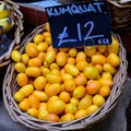 Fresh ripe orange kumkuat fruits displayed with black label and price in a wooden box, at a street food market, ready to eat exoti