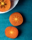 Fresh ripe, orange persimmons slices on a wooden background.