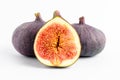 Fresh ripe organic figs on a white table, two whole figs and one sectioned in half, close up with soft focus, side view Royalty Free Stock Photo