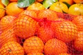 Fresh ripe organic mandarins in plastic mesh sack on olive wood and burlap