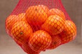 Fresh ripe organic mandarins in plastic mesh sack on olive wood and burlap