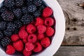 Fresh ripe organic raspberries and blackberries closeup in a bowl on a wooden background Royalty Free Stock Photo