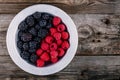 Fresh ripe organic raspberries and blackberries in a bowl on a wooden background Royalty Free Stock Photo