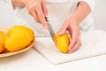 Fresh ripe organic yellow mangoes close up. Woman cutting mango on white cutting board Royalty Free Stock Photo