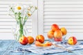 fresh ripe peaches in bowl on blue wooden table and daisy in vase Royalty Free Stock Photo