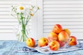 fresh ripe peaches in bowl on blue wooden table and daisy in vase Royalty Free Stock Photo