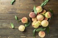 Fresh ripe peaches with leaves in a bowl on a wooden table, top view Royalty Free Stock Photo