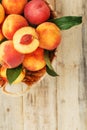 Peaches in a basket on a wooden background with a slice of sliced juicy peach with a stone Royalty Free Stock Photo