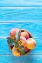 Fresh ripe peaches in a wooden bowl on a blue wooden background. Royalty Free Stock Photo