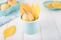 Fresh ripe pear and yellow autumn leaves in enameled cup on a white background. Toned photo. Copy space Royalty Free Stock Photo