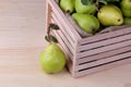 Fresh ripe pears in a wooden box on a natural wooden background