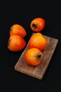 Fresh ripe persimmon on a black background . Persimmons fruit, Ripe sweet persimmons Royalty Free Stock Photo