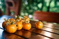 Fresh ripe persimmons lie on a wooden table near the bench in the gazebo in the garden Royalty Free Stock Photo