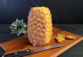 Fresh ripe pineapple being peeled on a wooden cutting board