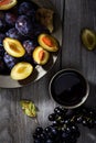 Fresh ripe plum in a plate and grapes on an old wooden table. Dark background Royalty Free Stock Photo