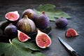 Fresh ripe purple figs with leaves on the table. Whole and sliced fruits and knife on dark background. Low key photo. Close-up. Royalty Free Stock Photo