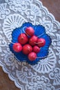 Fresh ripe radishes in a blue glass salad bowl on a wooden table with beautiful white tablecloth. Top view Royalty Free Stock Photo