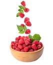 Fresh ripe raspberries falling with green leaves into bowl on background Royalty Free Stock Photo