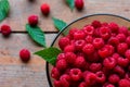 Fresh ripe raspberries with leaves in a bowl on a wooden background Royalty Free Stock Photo