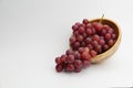 Fresh and ripe red grapes in a wooden bowl, isolated in white background. Bunch of raw and juicy grapevines