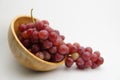 Fresh and ripe red grapes in a wooden bowl, isolated in white background. Bunch of raw and juicy grapevines Royalty Free Stock Photo