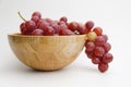 Fresh and ripe red grapes in a wooden bowl, isolated in white background. Bunch of raw and juicy grapevines Royalty Free Stock Photo