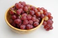 Fresh and ripe red grapes in a wooden bowl, isolated in white background. Bunch of raw and juicy grapevines Royalty Free Stock Photo