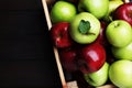 Fresh ripe red and green apples in wooden crate on black table, top view. Space for text Royalty Free Stock Photo