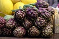 Fresh ripe red purple organic globe artichokes displayed for sale at a street food market, side view of healthy vegan food photogr Royalty Free Stock Photo