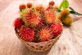Fresh ripe red rambutans fruit in basket on wood floor Royalty Free Stock Photo