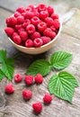 Fresh ripe red raspberries with leaves in a bowl on rustic old wooden table. Royalty Free Stock Photo