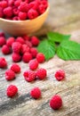 Fresh ripe red raspberries with leaves in a bowl on rustic old wooden table. Royalty Free Stock Photo