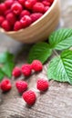 Fresh ripe red raspberries with leaves in a bowl on rustic old wooden table. Royalty Free Stock Photo