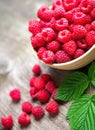 Fresh ripe red raspberries with leaves in a bowl on rustic old wooden table. Healthy organic food, summer vitamins, BIO viands Royalty Free Stock Photo