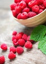 Fresh ripe red raspberries with leaves in a bowl on rustic old wooden table. Healthy organic food, summer vitamins, BIO viands Royalty Free Stock Photo