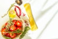 Fresh Ripe Red Tomatoes Rosemary Thyme in Wicker Basket Olive Oil in Bottle Spaghetti Hot Peppers on White Table. Italian cuisine Royalty Free Stock Photo