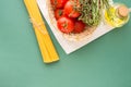 Fresh Ripe Red Tomatoes Rosemary Thyme in Wicker Basket Olive Oil in Bottle Spaghetti on White Napkin Green Background. Italian Royalty Free Stock Photo