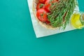 Fresh Ripe Red Tomatoes Rosemary Thyme in Wicker Basket Olive Oil in Bottle on White Napkin Green Background Italian Cuisine Royalty Free Stock Photo