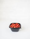 Fresh ripe red wild strawberries in a black plastic container on a white background. Copy space Royalty Free Stock Photo