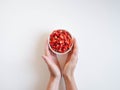 Fresh ripe red wild strawberries in a white ceramic bowl and woman hands on a white background. Top view Royalty Free Stock Photo