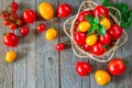 Fresh ripe red and yellow tomatoes in a wicker plate on a wooden table Royalty Free Stock Photo