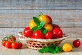 Fresh ripe red and yellow tomatoes in a wicker plate on a wooden table Royalty Free Stock Photo