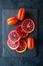 Fresh ripe slices of blood oranges and macarons on a black slate Royalty Free Stock Photo